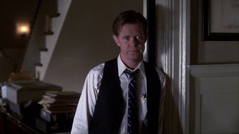 Movie still from “A Civil Action” (1998), directed by Steven Zaillian – A man wearing a vest and tie standing in front of a wall; Medium shot, Over the shoulder angle