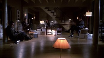 Movie still from “A Civil Action” (1998), directed by Steven Zaillian – A group of people sitting in a living room next to a lamp; Wide shot, High angle
