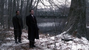 Movie still from “A Civil Action” (1998), directed by Steven Zaillian – A man standing in the snow next to a bridge; Wide shot, Over the shoulder angle