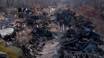 Movie still from “A Civil Action” (1998), directed by Steven Zaillian – Two people standing on a dirt path near a pile of trash; Extreme Wide shot, High angle
