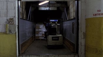 Movie still from “A Civil Action” (1998), directed by Steven Zaillian – A man riding on the back of a forklift in a warehouse; Wide shot, High angle