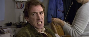 Movie still from “Tristram Shandy” (2005), directed by Michael Winterbottom – A person with a knife in his mouth; Close Up shot, High angle