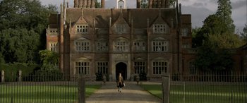 Movie still from “Tristram Shandy” (2005), directed by Michael Winterbottom – A woman walking down a path in front of a large building; Extreme Wide shot, High angle