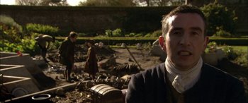 Movie still from “Tristram Shandy” (2005), directed by Michael Winterbottom – A man sitting in front of a pile of rubble; Close Up shot, Over the shoulder angle
