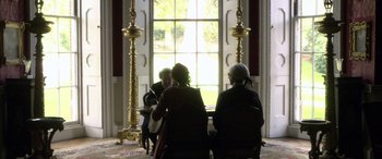 Movie still from “Tristram Shandy” (2005), directed by Michael Winterbottom – A group of people sitting in front of a large window; Wide shot, High angle