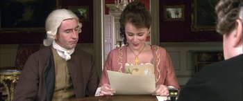 Movie still from “Tristram Shandy” (2005), directed by Michael Winterbottom – A young woman sitting at a table reading a letter; Medium shot, High angle