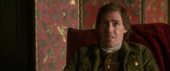 Movie still from “Tristram Shandy” (2005), directed by Michael Winterbottom – A person sitting in a chair; Close Up shot, Over the shoulder angle