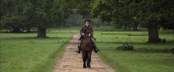Movie still from “Tristram Shandy” (2005), directed by Michael Winterbottom – A man riding on the back of a horse down a dirt road; Wide shot, Over the shoulder angle