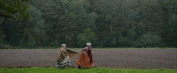 Movie still from “Tristram Shandy” (2005), directed by Michael Winterbottom – Two people walking in a field holding hands; Extreme Wide shot, High angle