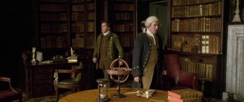 Movie still from “Tristram Shandy” (2005), directed by Michael Winterbottom – Two men dressed in period costumes in a library; Medium shot, High angle