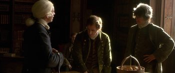 Movie still from “Tristram Shandy” (2005), directed by Michael Winterbottom – A man in a green jacket standing next to another man in a green jacket; Medium shot, Over the shoulder angle