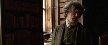 Movie still from “Tristram Shandy” (2005), directed by Michael Winterbottom – A man standing in front of a window in a room; Medium shot, Over the shoulder angle