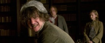 Movie still from “Tristram Shandy” (2005), directed by Michael Winterbottom – A man in a wig and a hat is in a library; Close Up shot, Over the shoulder angle