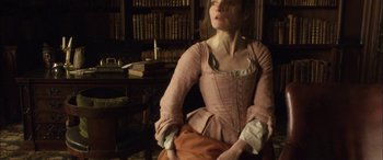 Movie still from “Tristram Shandy” (2005), directed by Michael Winterbottom – A woman in a pink dress is holding a purse; Medium shot, Low angle