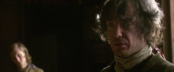 Movie still from “Tristram Shandy” (2005), directed by Michael Winterbottom – A person wearing a suit and tie; Close Up shot, Over the shoulder angle