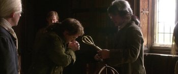 Movie still from “Tristram Shandy” (2005), directed by Michael Winterbottom – A man holding a whisk in his hands while another man looks on; Medium shot, Over the shoulder angle