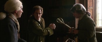 Movie still from “Tristram Shandy” (2005), directed by Michael Winterbottom – A man holding a pair of shears in his hands; Medium shot, Over the shoulder angle