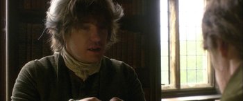 Movie still from “Tristram Shandy” (2005), directed by Michael Winterbottom – A man sitting at a table in front of a window; Close Up shot, High angle