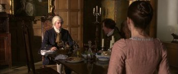 Movie still from “Tristram Shandy” (2005), directed by Michael Winterbottom – A group of people sitting at a table with plates of food; Medium shot, High angle