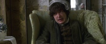 Movie still from “Tristram Shandy” (2005), directed by Michael Winterbottom – A man sitting in a chair wearing a wig; Close Up shot, High angle