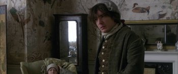 Movie still from “Tristram Shandy” (2005), directed by Michael Winterbottom – A man standing in front of a mirror in a room; Medium shot, Over the shoulder angle