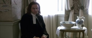 Movie still from “Tristram Shandy” (2005), directed by Michael Winterbottom – A man sitting in front of a window wearing a robe; Medium shot, High angle