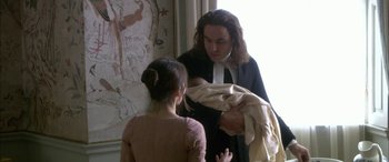 Movie still from “Tristram Shandy” (2005), directed by Michael Winterbottom – A man holding a baby in his arms while standing next to a woman; Medium shot, High angle