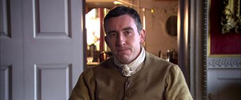 Movie still from “Tristram Shandy” (2005), directed by Michael Winterbottom – A person wearing a suit and tie; Close Up shot, Over the shoulder angle