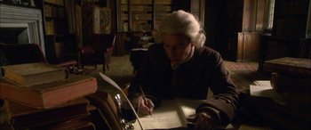 Movie still from “Tristram Shandy” (2005), directed by Michael Winterbottom – A man writing on a piece of paper in a library; Medium shot, High angle