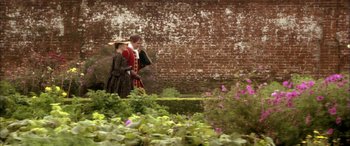 Movie still from “Tristram Shandy” (2005), directed by Michael Winterbottom – Two people dressed in period clothing standing in a garden; Wide shot, High angle