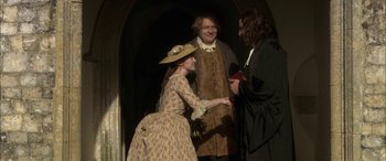 Movie still from “Tristram Shandy” (2005), directed by Michael Winterbottom – A woman in a dress and a man in a suit and tie; Medium shot, Over the shoulder angle