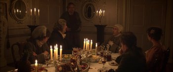 Movie still from “Tristram Shandy” (2005), directed by Michael Winterbottom – A group of people sitting around a dinner table with lit candles; Medium shot, High angle
