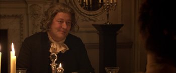 Movie still from “Tristram Shandy” (2005), directed by Michael Winterbottom – A man sitting at a table with a candle in front of him; Close Up shot, Over the shoulder angle