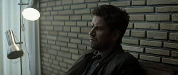 Movie still from “Department Q: A Conspiracy of Faith” (2016), directed by Hans Petter Moland – A person wearing a suit and tie near a brick wall; Close Up shot, Low angle