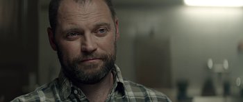 Movie still from “Department Q: A Conspiracy of Faith” (2016), directed by Hans Petter Moland – A person wearing a plaid shirt; Close Up shot, Over the shoulder angle