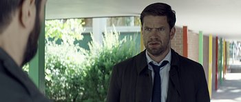 Movie still from “Department Q: A Conspiracy of Faith” (2016), directed by Hans Petter Moland – A person wearing a suit and tie; Close Up shot, Over the shoulder angle