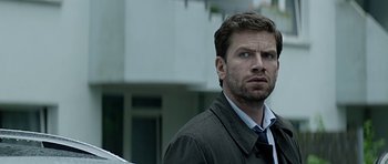 Movie still from “Department Q: A Conspiracy of Faith” (2016), directed by Hans Petter Moland – A person wearing a suit and tie; Close Up shot, Over the shoulder angle