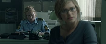 Movie still from “Department Q: A Conspiracy of Faith” (2016), directed by Hans Petter Moland – Two women sitting at a desk in a room; Medium shot, Over the shoulder angle