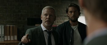Movie still from “Department Q: A Conspiracy of Faith” (2016), directed by Hans Petter Moland – A man and a man standing next to each other; Medium shot, Over the shoulder angle