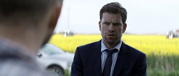 Movie still from “Department Q: A Conspiracy of Faith” (2016), directed by Hans Petter Moland – A person wearing a suit and tie; Close Up shot, Over the shoulder angle