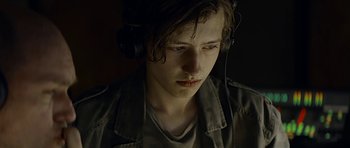 Movie still from “Department Q: A Conspiracy of Faith” (2016), directed by Hans Petter Moland – A young man wearing headphones and looking down; Close Up shot, Over the shoulder angle