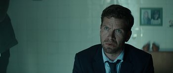 Movie still from “Department Q: A Conspiracy of Faith” (2016), directed by Hans Petter Moland – A person wearing a suit and tie; Close Up shot, Over the shoulder angle