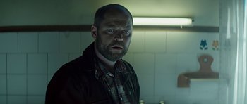 Movie still from “Department Q: A Conspiracy of Faith” (2016), directed by Hans Petter Moland – A man with a goatee standing in a kitchen; Close Up shot, Over the shoulder angle