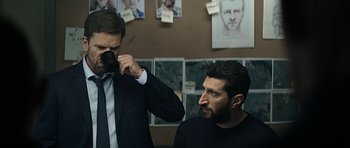 Movie still from “Department Q: A Conspiracy of Faith” (2016), directed by Hans Petter Moland – A man taking a picture of another man with a camera; Medium shot, Over the shoulder angle