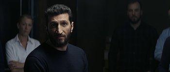 Movie still from “Department Q: A Conspiracy of Faith” (2016), directed by Hans Petter Moland – A man with a beard is standing in a dark room; Close Up shot, Over the shoulder angle
