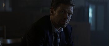 Movie still from “Department Q: A Conspiracy of Faith” (2016), directed by Hans Petter Moland – A person wearing a suit and tie; Close Up shot, Over the shoulder angle