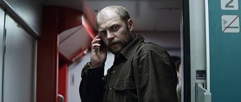 Movie still from “Department Q: A Conspiracy of Faith” (2016), directed by Hans Petter Moland – A man with a bald head talking on a cell phone; Close Up shot, Low angle