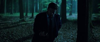 Movie still from “Department Q: A Conspiracy of Faith” (2016), directed by Hans Petter Moland – A man wearing a suit and tie standing in the woods; Medium shot, Low angle