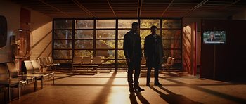 Movie still from “Department Q: A Conspiracy of Faith” (2016), directed by Hans Petter Moland – Two men are standing in front of a large window; Wide shot, Low angle