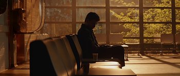 Movie still from “Department Q: A Conspiracy of Faith” (2016), directed by Hans Petter Moland – A man sitting at a table in front of a laptop; Wide shot, Low angle